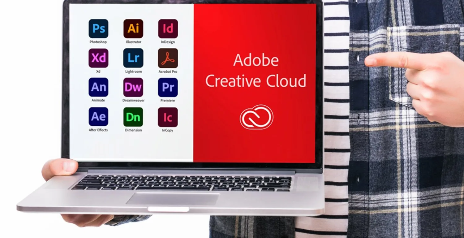 A laptop showing Adobe Creative Cloud app icons, including Photoshop, Illustrator, InDesign and Premiere Pro, held by a person pointing at the screen