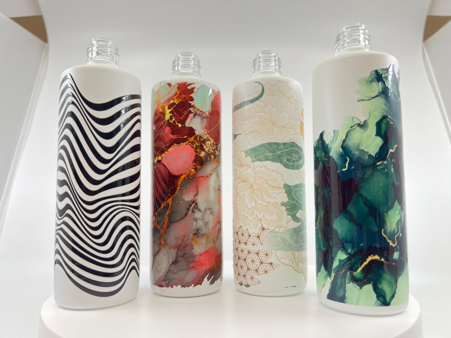Four cylindrical containers each printed with different full-colour artwork wrapping the whole body