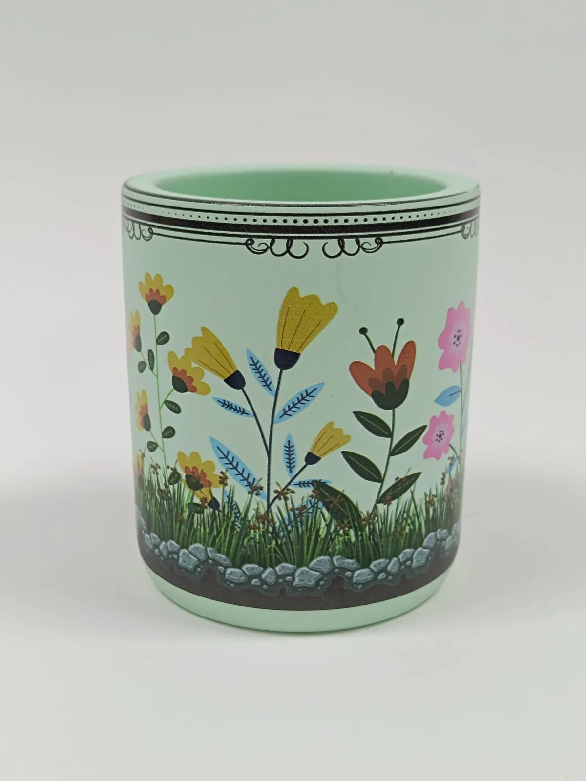 Mint-coloured candle jar printed all round with a full-colour garden design and patterned borders, printed after the wax was poured