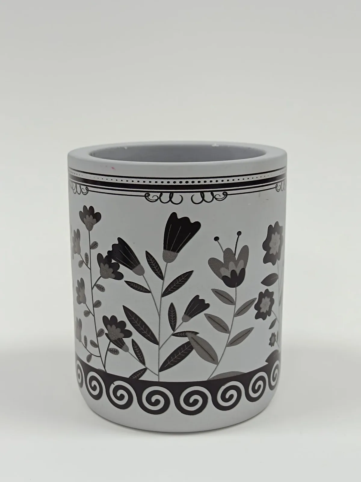 Grey candle jar printed with a single dark-colour floral design and a scroll border after the wax was poured