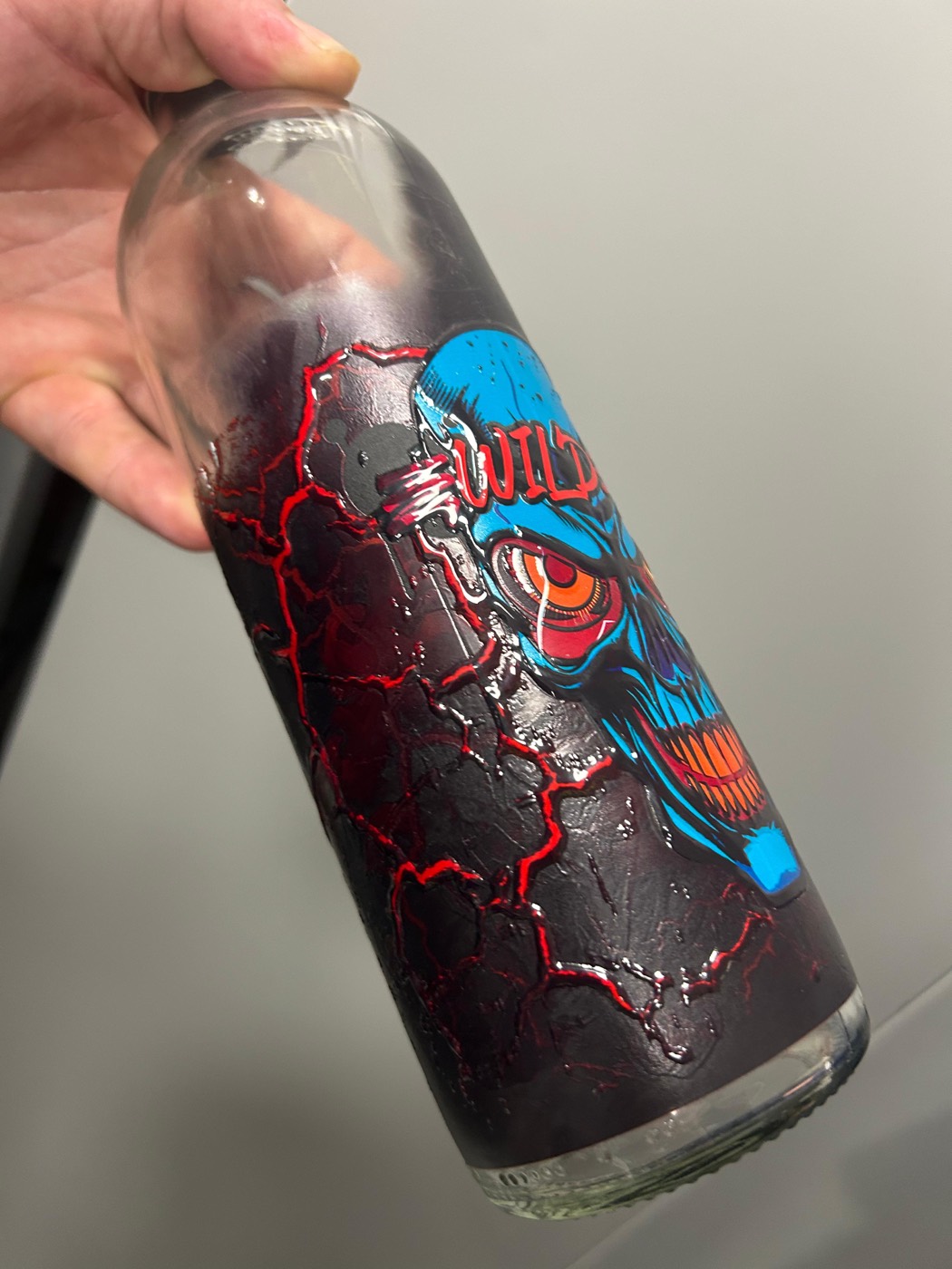 Clear glass bottle printed directly with full-colour artwork and a raised tactile relief that can be felt on the glass surface