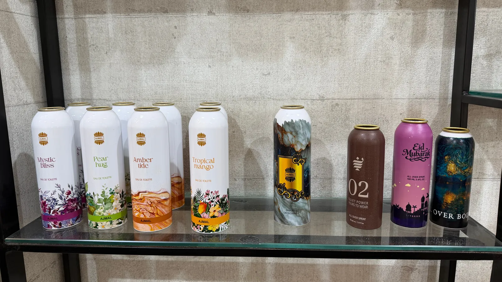 Rows of directly printed aluminium eau de toilette and all-over body spray cans on a sample shelf in Dubai, printed 360 degrees on an LSINC cylindrical printer with no label