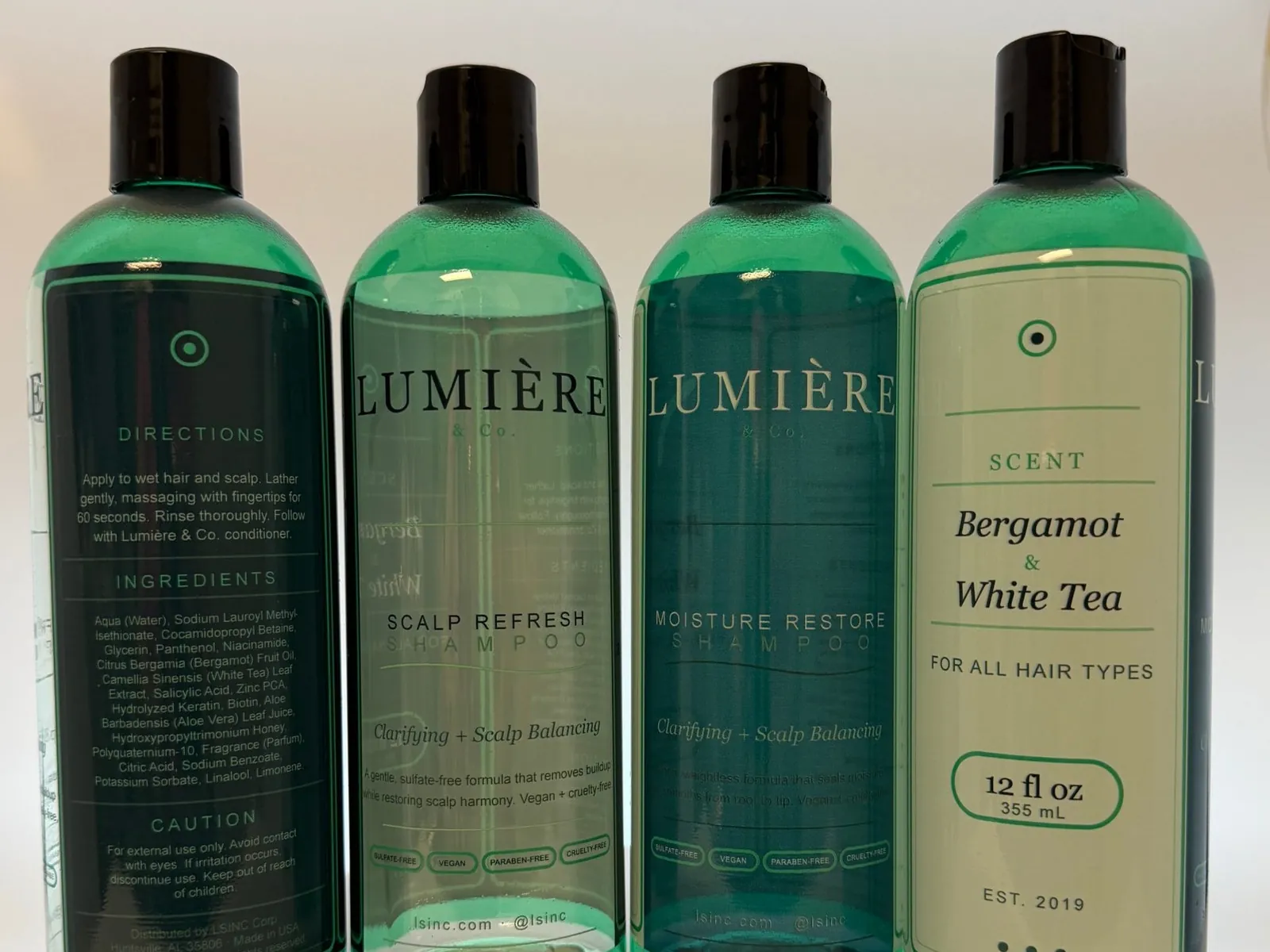 Four green PET shampoo bottles printed directly with a full label design front and back, including the brand panel, directions, ingredients and a barcode