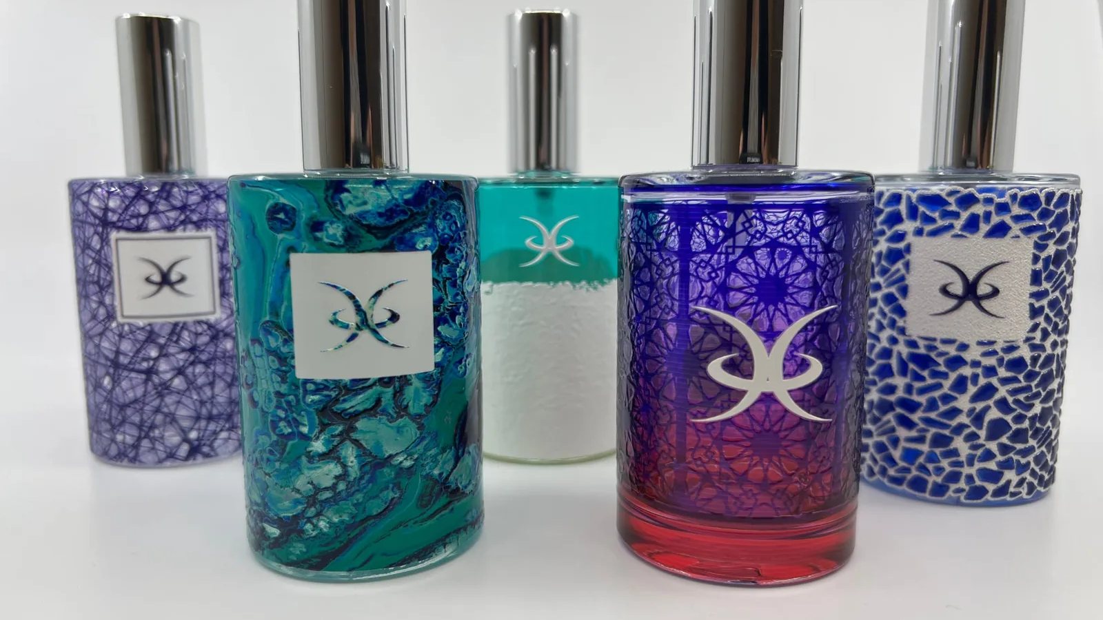 Round glass perfume bottles printed all round with blue, teal and purple patterns, LSINC demonstration bottles