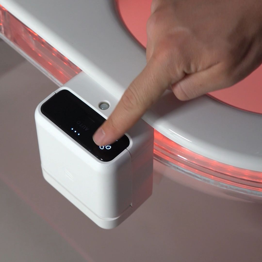 Finger pressing the fan button on the touch panel of an AirCube fitted to a toilet rim