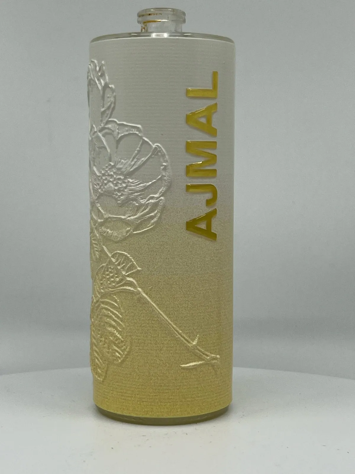 Cream fragrance bottle with raised gold lettering and a raised floral relief built in cured ink, showing a 3D embossed tactile finish