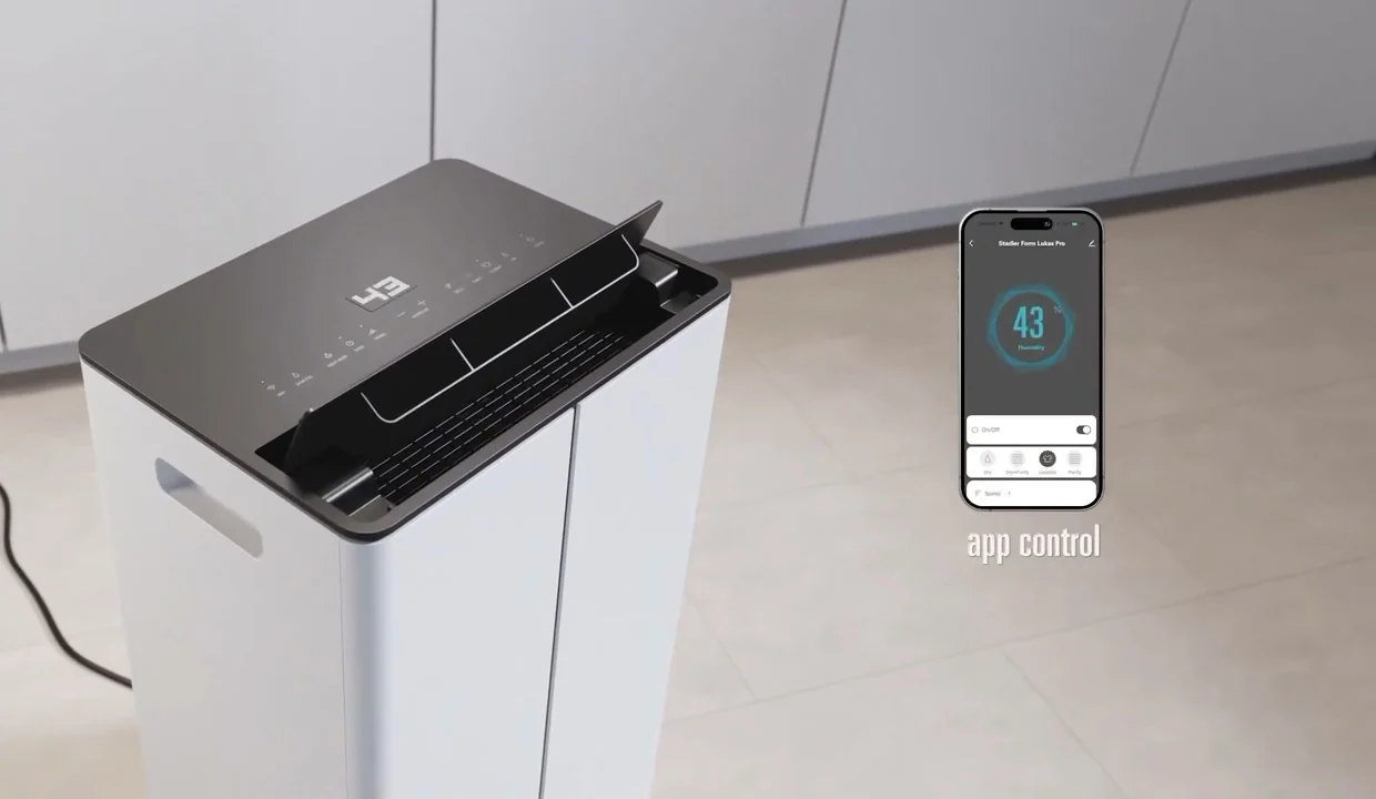 Top panel of a white Stadler Form Lukas Pro dehumidifier showing 43 on its display, beside a phone running the Stadler Form app that also reads 43