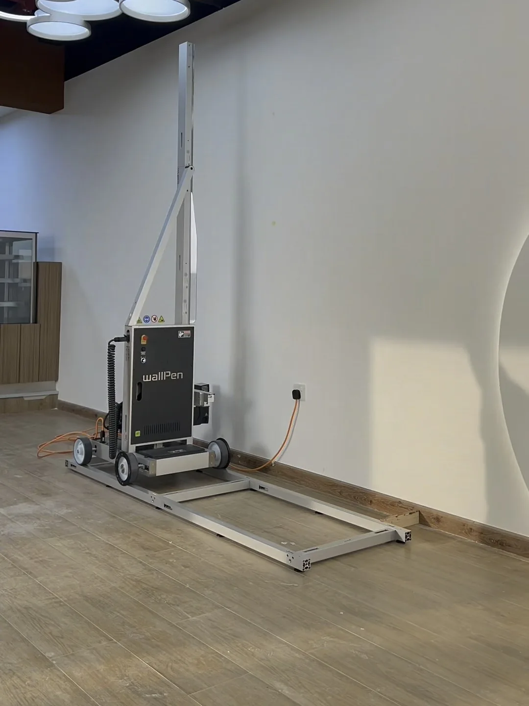 A wallPen E2 standing on its aluminium floor rail in front of a blank white wall, ready to print, at a gym in Abu Dhabi