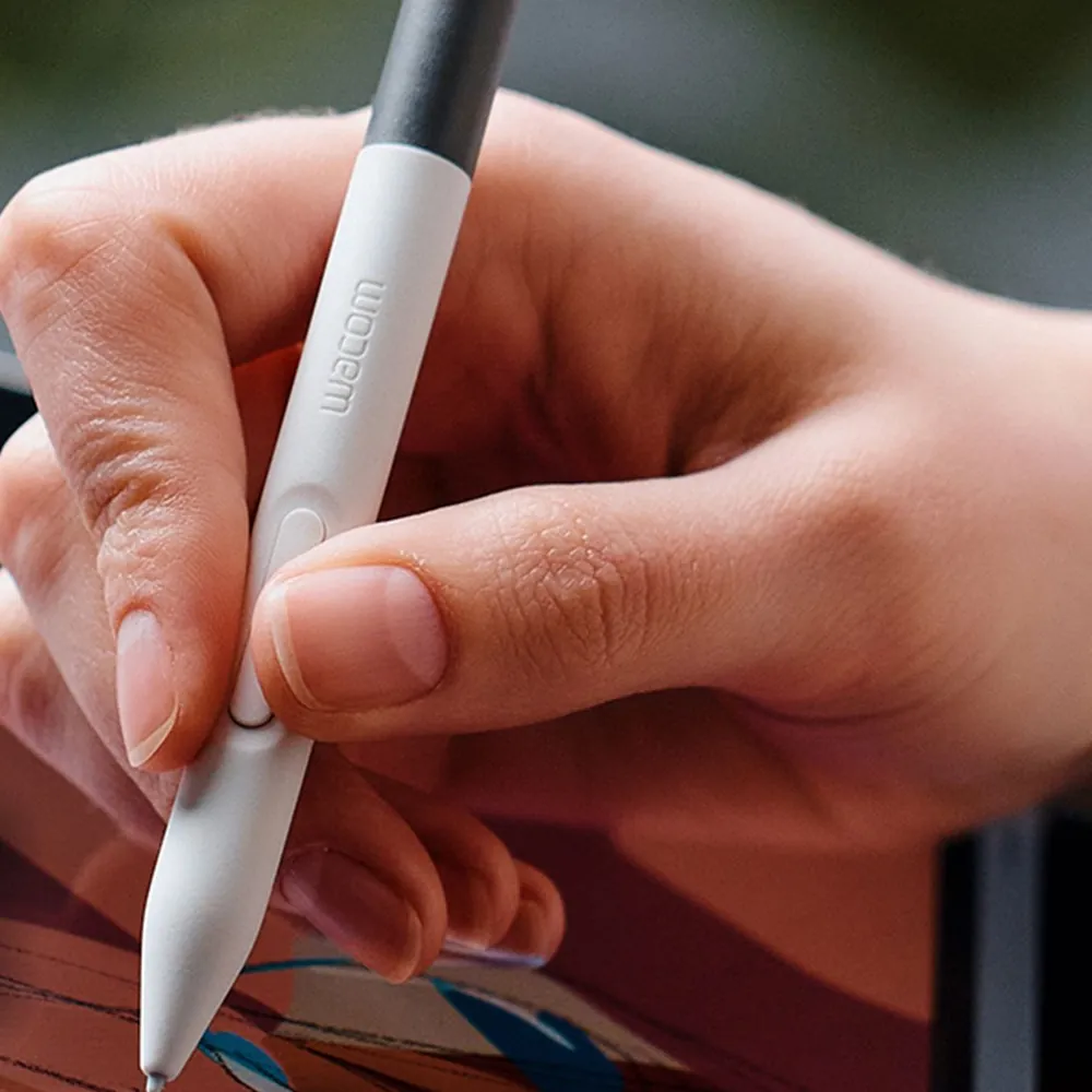 Close-up of a hand holding the Wacom One Standard Pen with its side button against a pen display