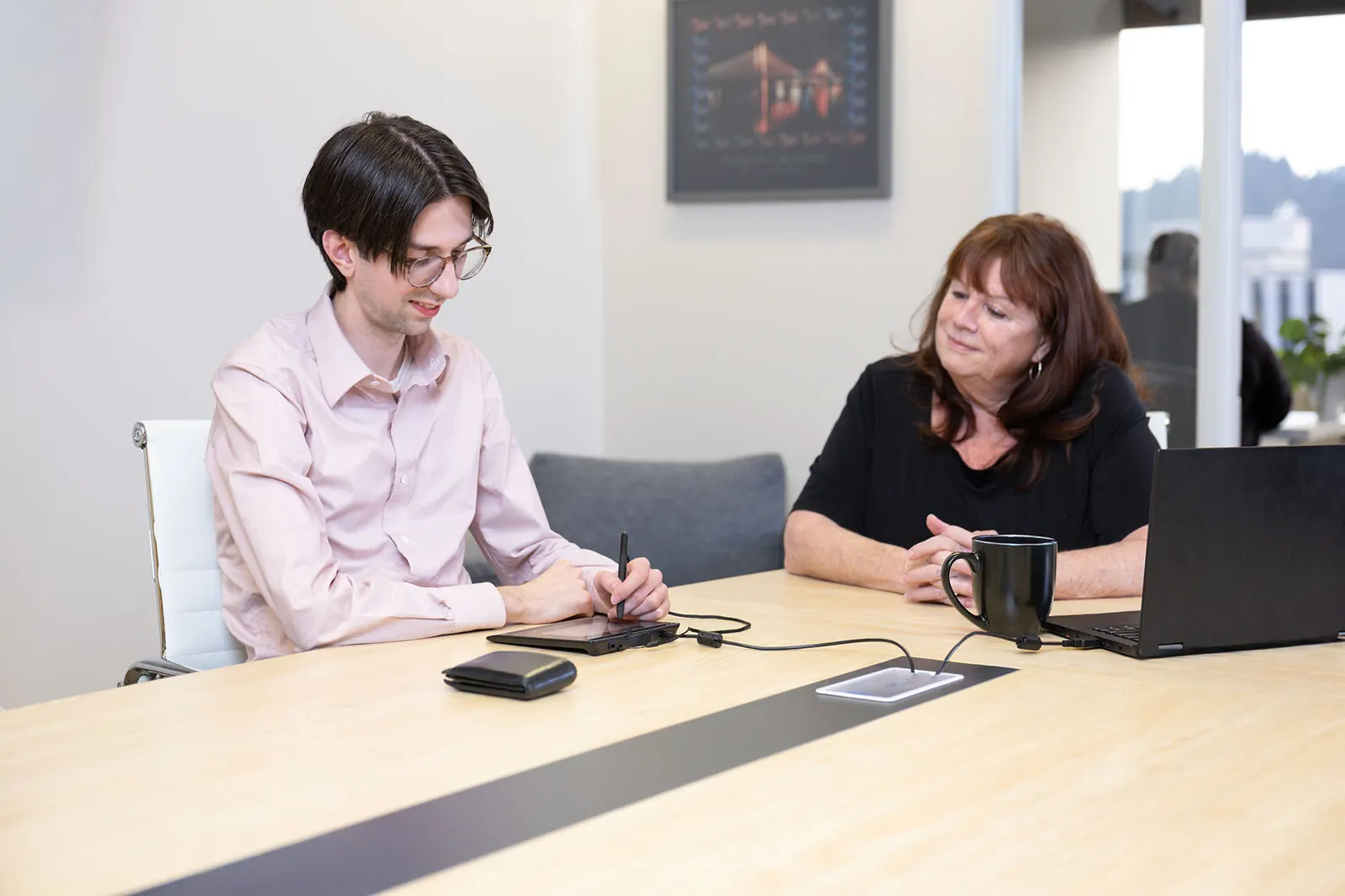 A customer signing on a Wacom STU-540 signature pad at a meeting table while an adviser looks on