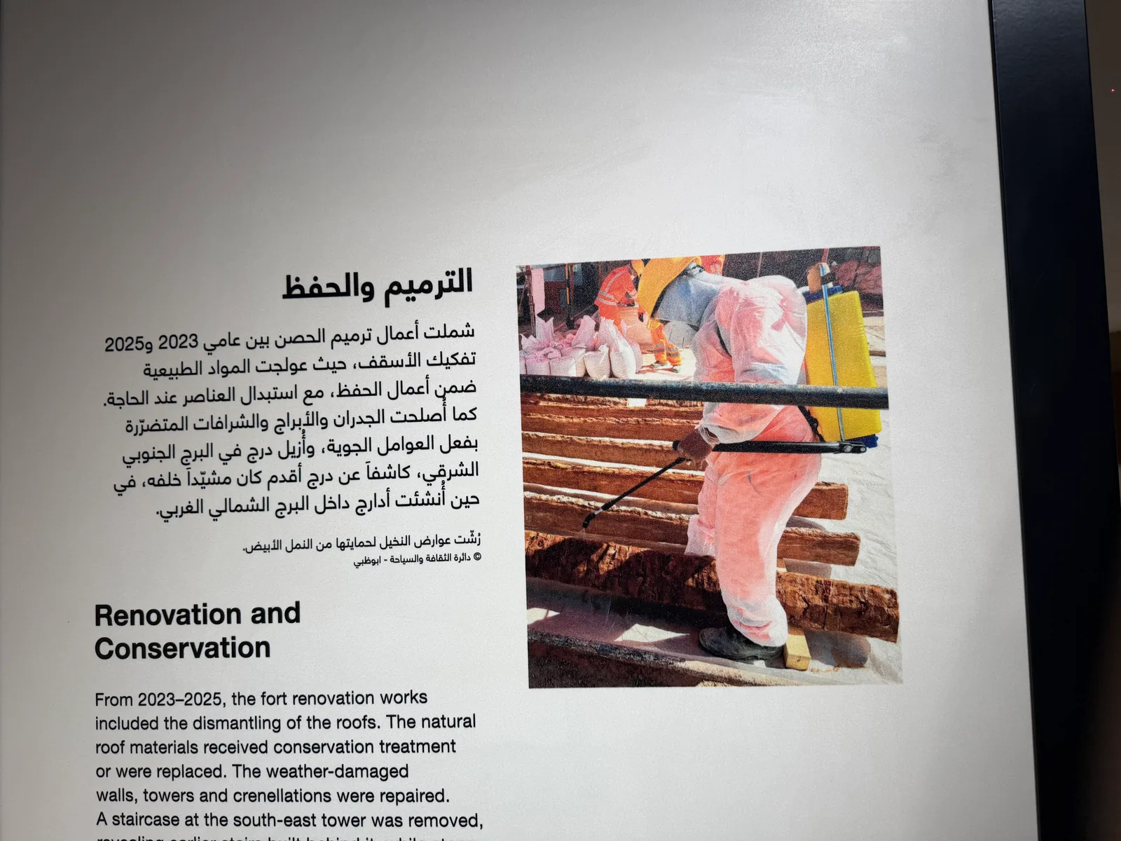 Bilingual Arabic and English interpretation panel with a photograph printed directly onto the plaster wall of a restored fort in the UAE
