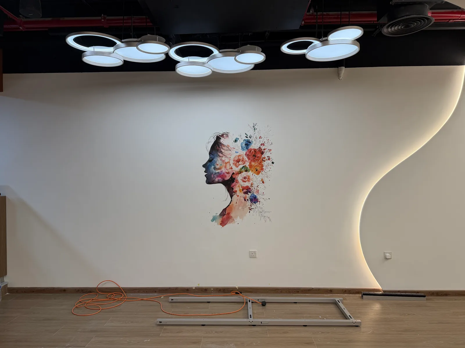 wallPen E2 floor rail and power cable laid along a curved gym reception wall in Abu Dhabi with the finished floral print behind