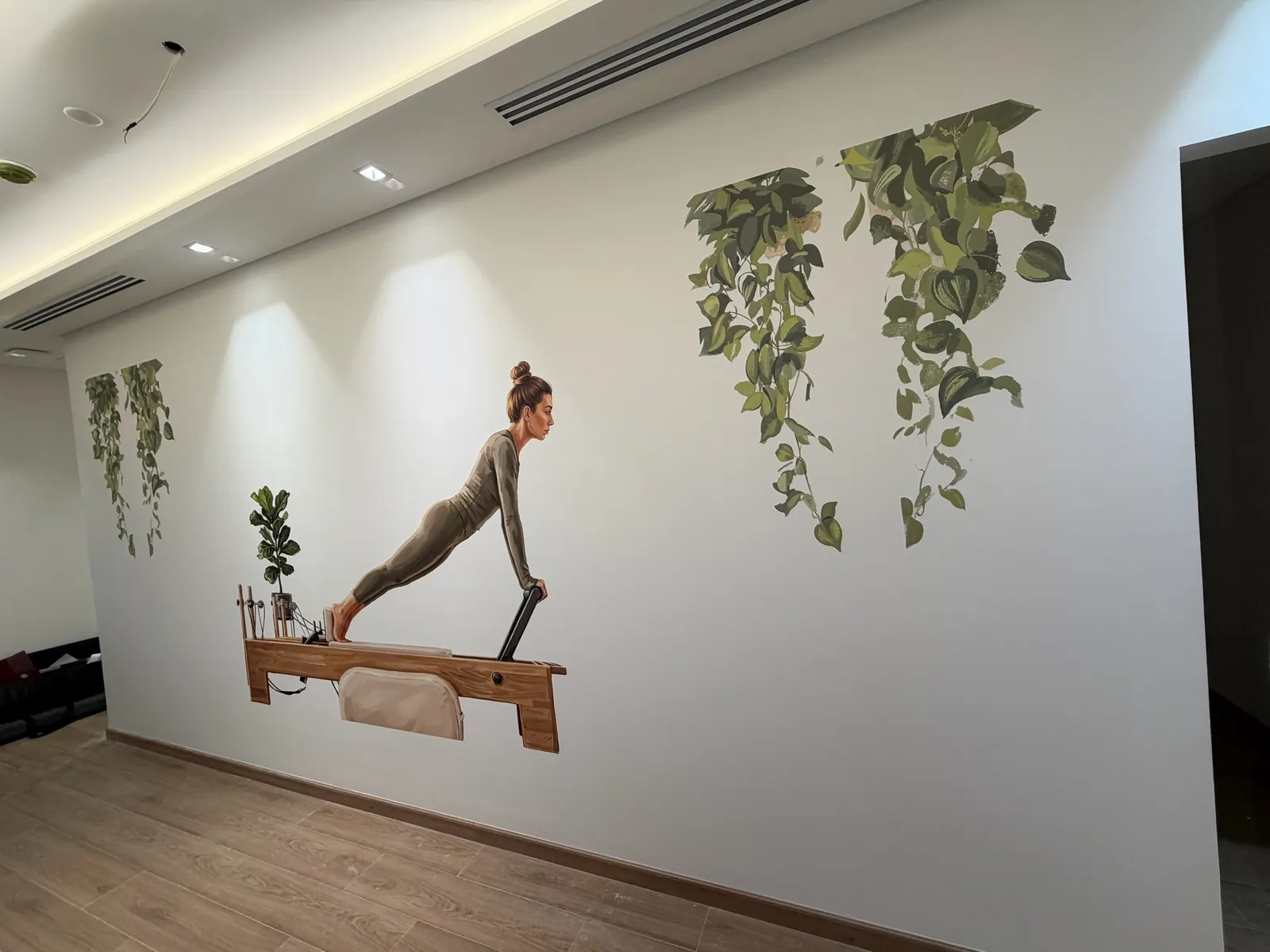 Pilates studio wall printed with a woman on a reformer and hanging plants