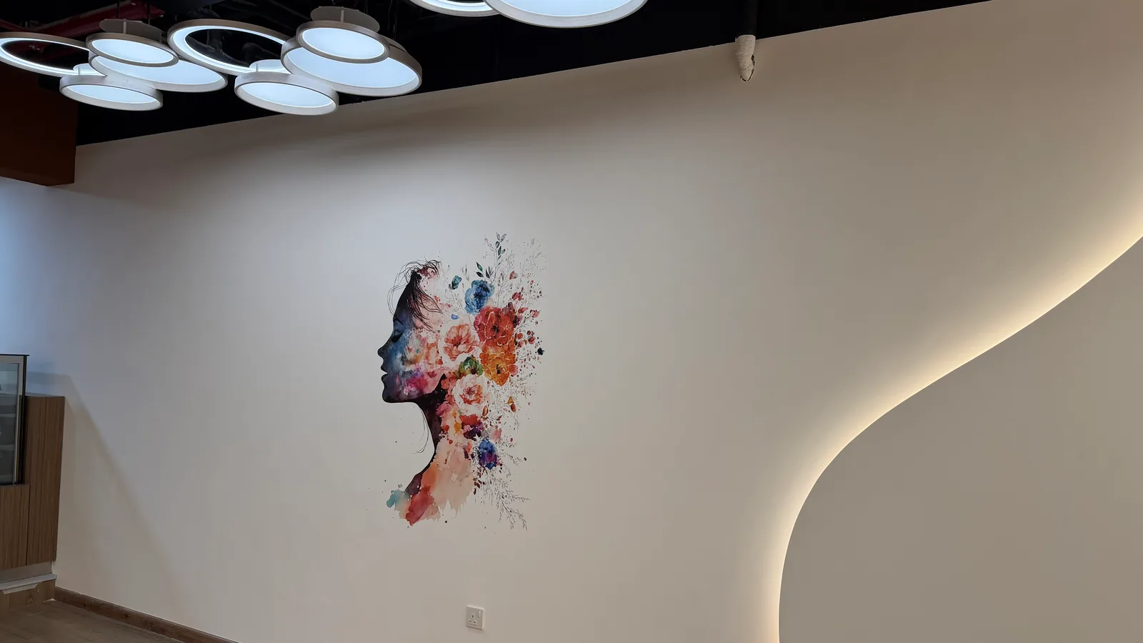 Floral profile artwork printed directly onto a curved white reception wall at a gym in Abu Dhabi by a wallPen E2