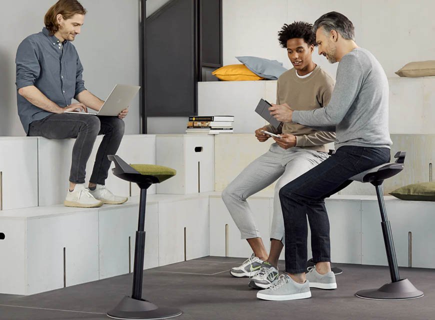 Two men sitting on Aeris Muvman standing chairs during an office discussion