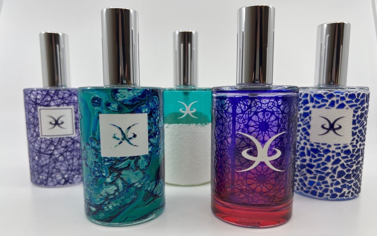 Five perfume bottles decorated by cylindrical UV printing, showing marbled, textured white, mandala and crackle finishes
