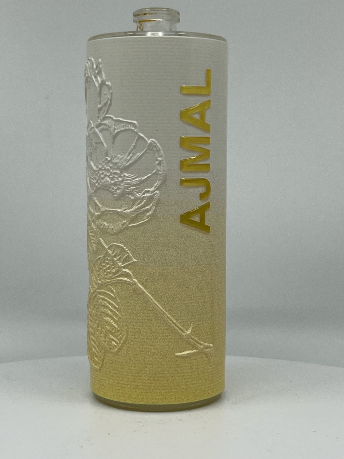 Perfume bottle printed with a raised white floral relief and gold lettering, showing tactile UV printing on glass