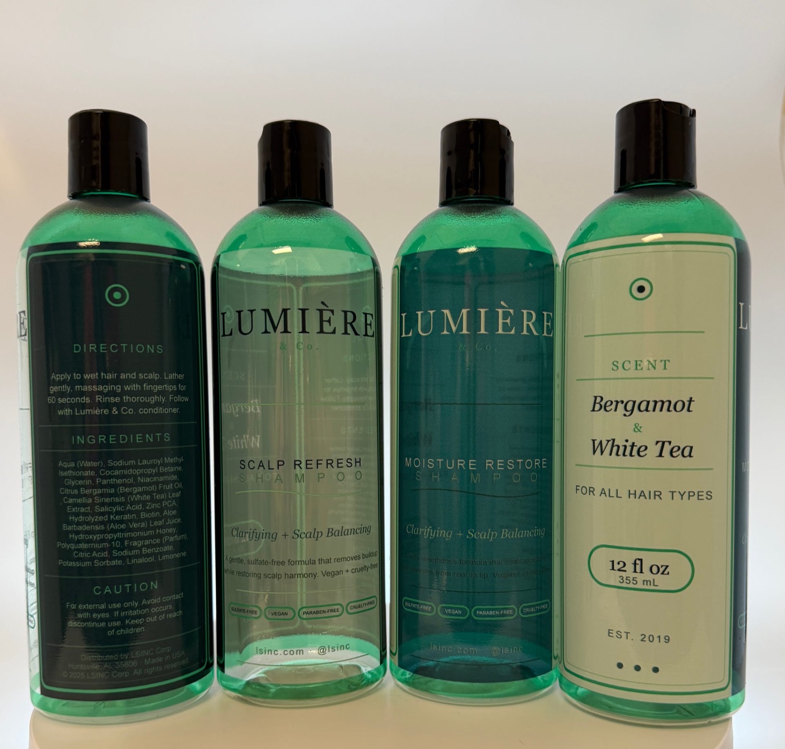 Four PET cosmetic and haircare bottles printed with brand artwork plus small ingredient and caution text directly on the plastic