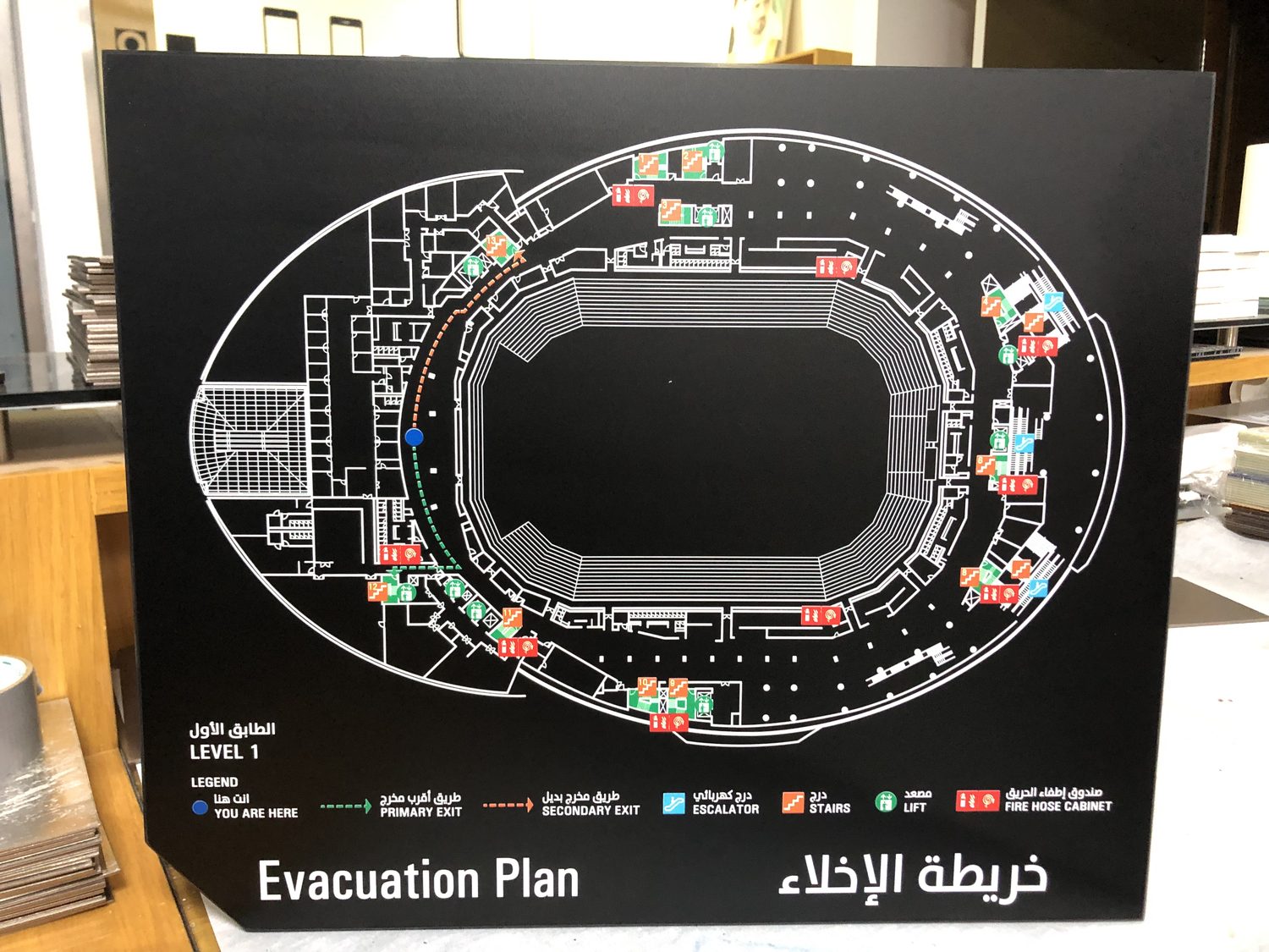 Stadium evacuation plan board printed on a UV flatbed printer, white and colour ink on a dark panel