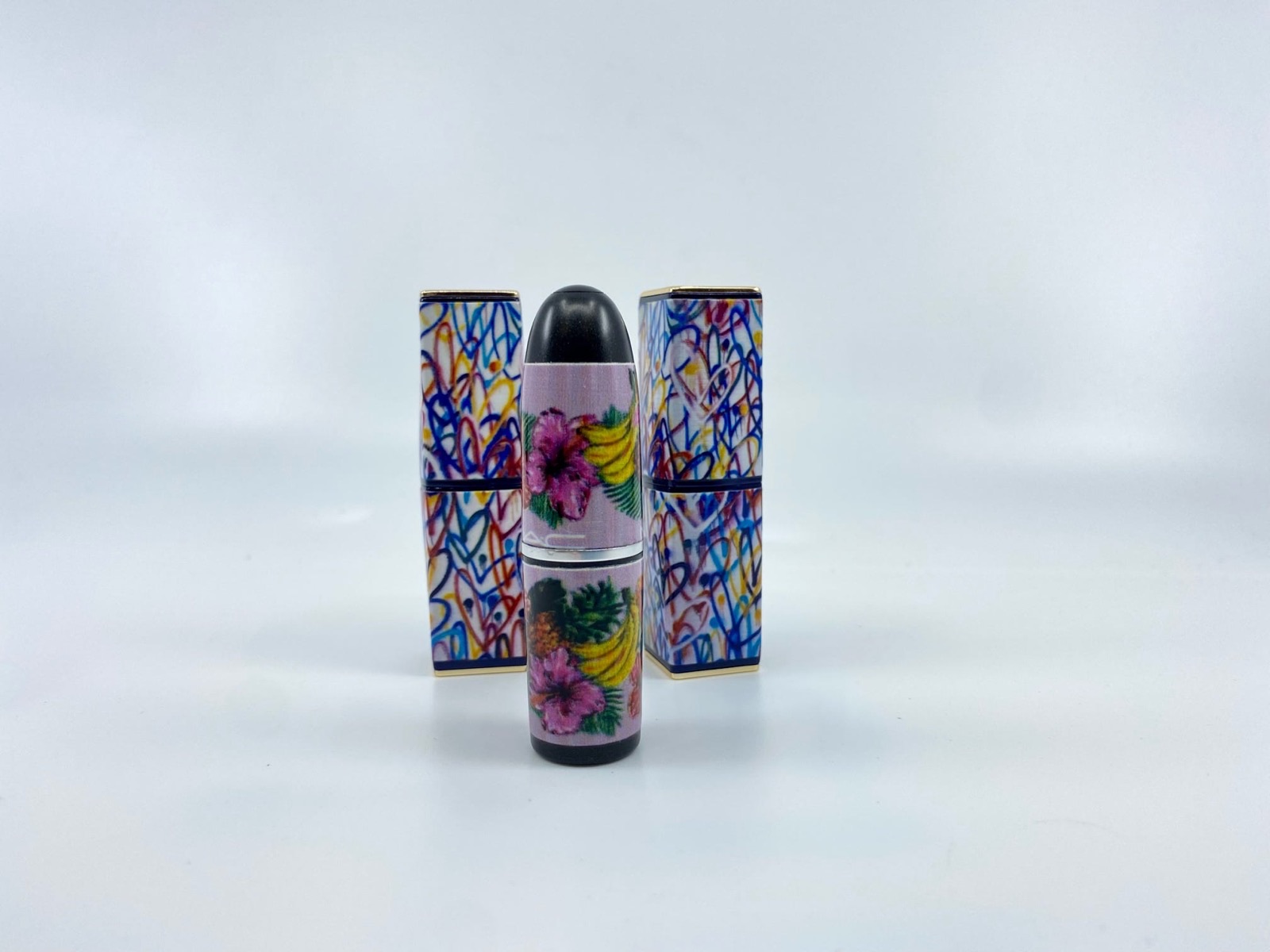 Printed cosmetic stick with full colour hibiscus artwork wrapping the barrel, standing in front of printed cardboard cartons in a matching pattern