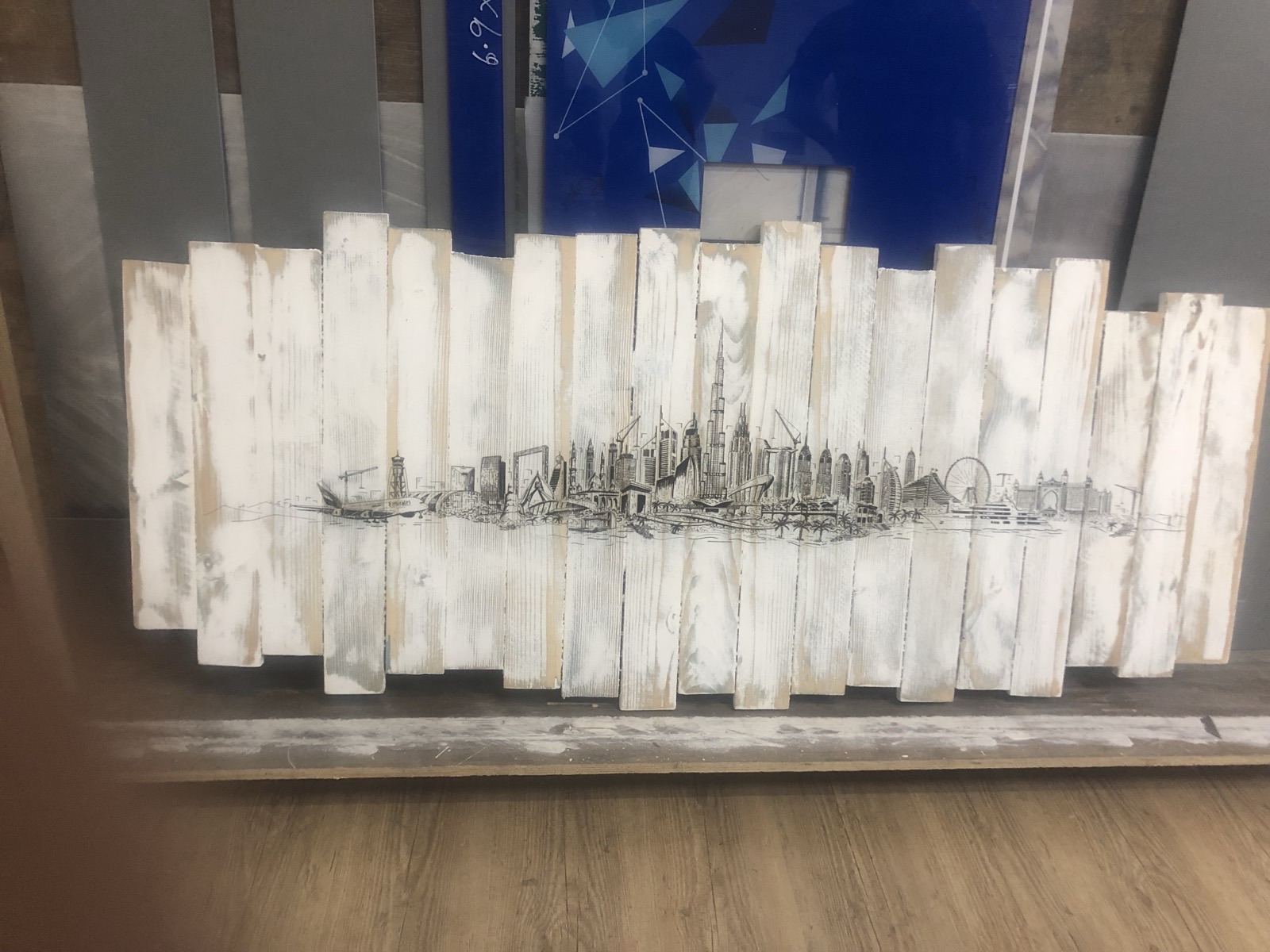 Fine line drawing of a city skyline printed straight onto a wall panel of whitewashed distressed wood slats, the ink sitting into the grain